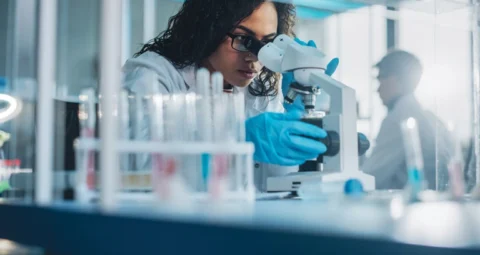 A scientist analyzing a sample through a microscope in a laboratory.