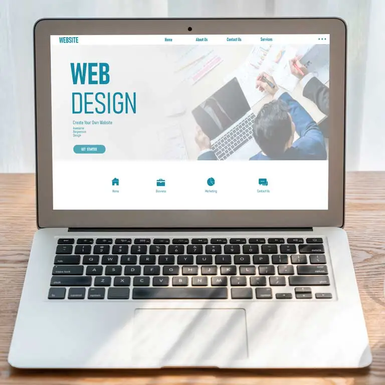 An open laptop on a wooden desk displaying a clean, modern web design template.